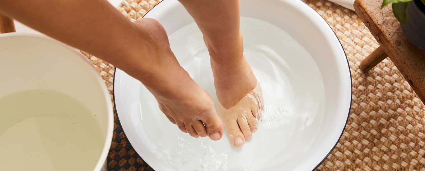 Bain de pieds dans une cuvette en verre avec des sels de bain